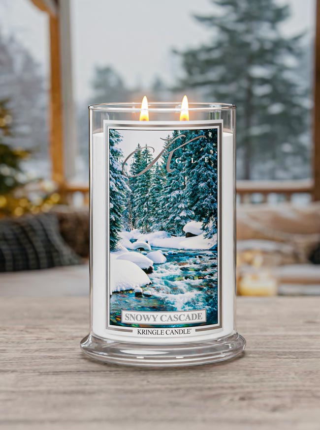 Candle with a 'Snowy Cascade' design on a wooden surface with a snowy landscape background.