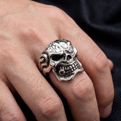 Close-up of a man wearing a silver mafia skull ring with a clear stone eye and red stone cigar.