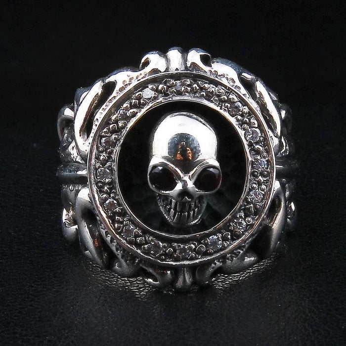 Front view of the gothic skull ring, garnet-eyed skull centered in a clear CZ halo framed by tribal scrollwork.