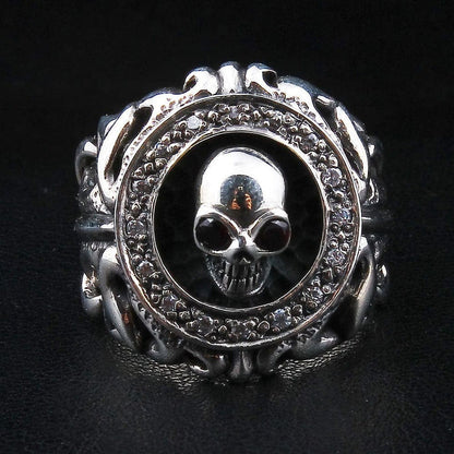 Front view of the gothic skull ring, garnet-eyed skull centered in a clear CZ halo framed by tribal scrollwork.