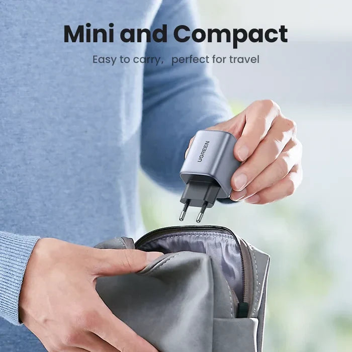 Compact silver wall charger or power adapter being held above a travel pouch.