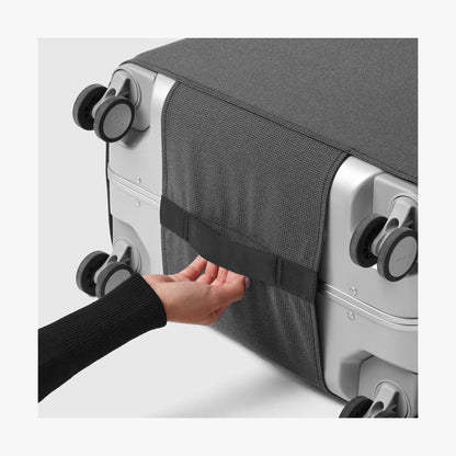 Carry-On | Hands on the hook-and-loop closure on the base panel of the grey Monos washable luggage cover around the wheels
