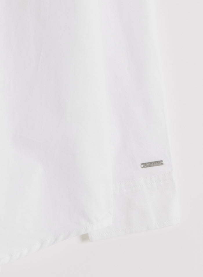 Close-up of a white cotton Oxford shirt sleeve featuring a subtle silver aim'n logo badge.