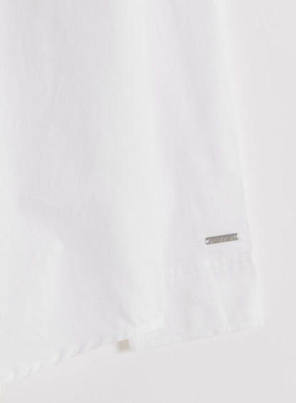 Close-up of a white cotton Oxford shirt sleeve featuring a subtle silver aim'n logo badge.