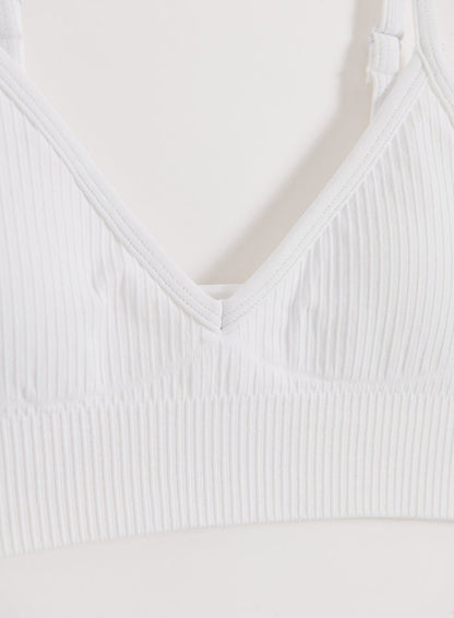 Close-up of a white Ribbed Seamless Deep Cut Bra by aim'n featuring a textured fabric and deep neckline.