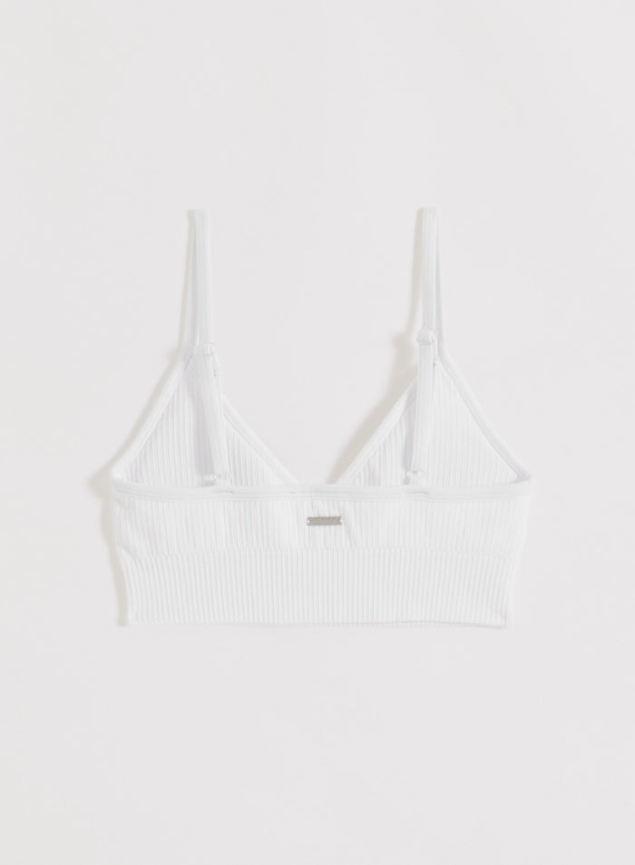 White ribbed seamless sports bra with adjustable straps and metal aim'n logo shown from the back.