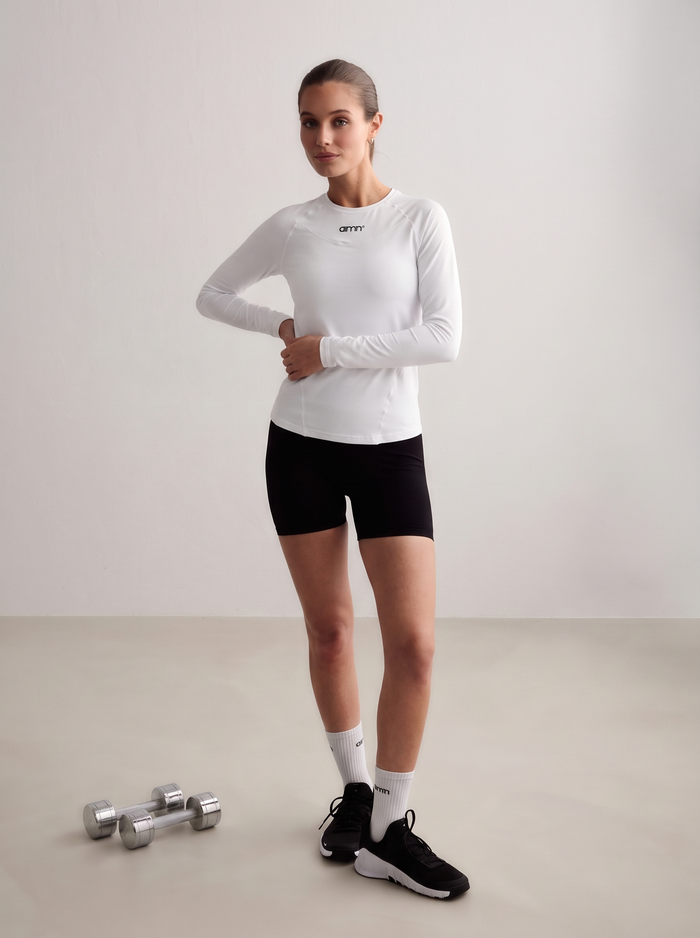 Model wearing a white Soft Basic Long Sleeve with black shorts and dumbbells [S-174 cm]