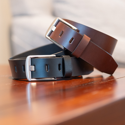 Two leather belts with metal buckles on a wooden surface