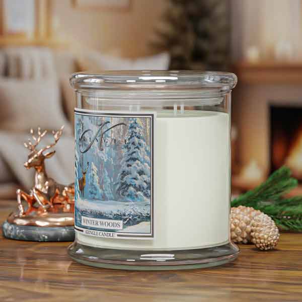 Candle with a 'Winter Woods' label on a wooden surface, surrounded by decorative items.