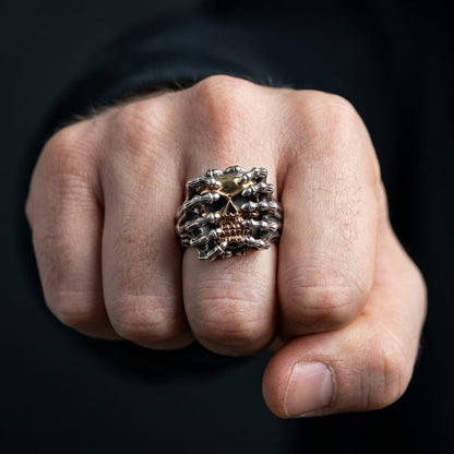 Man's clenched fist wearing a silver and yellow gold spider skull ring.